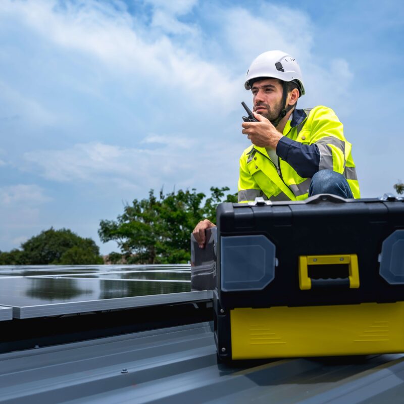 man-working-on-solar-panels-on-top-of-roof-whilst-wearing-PPE